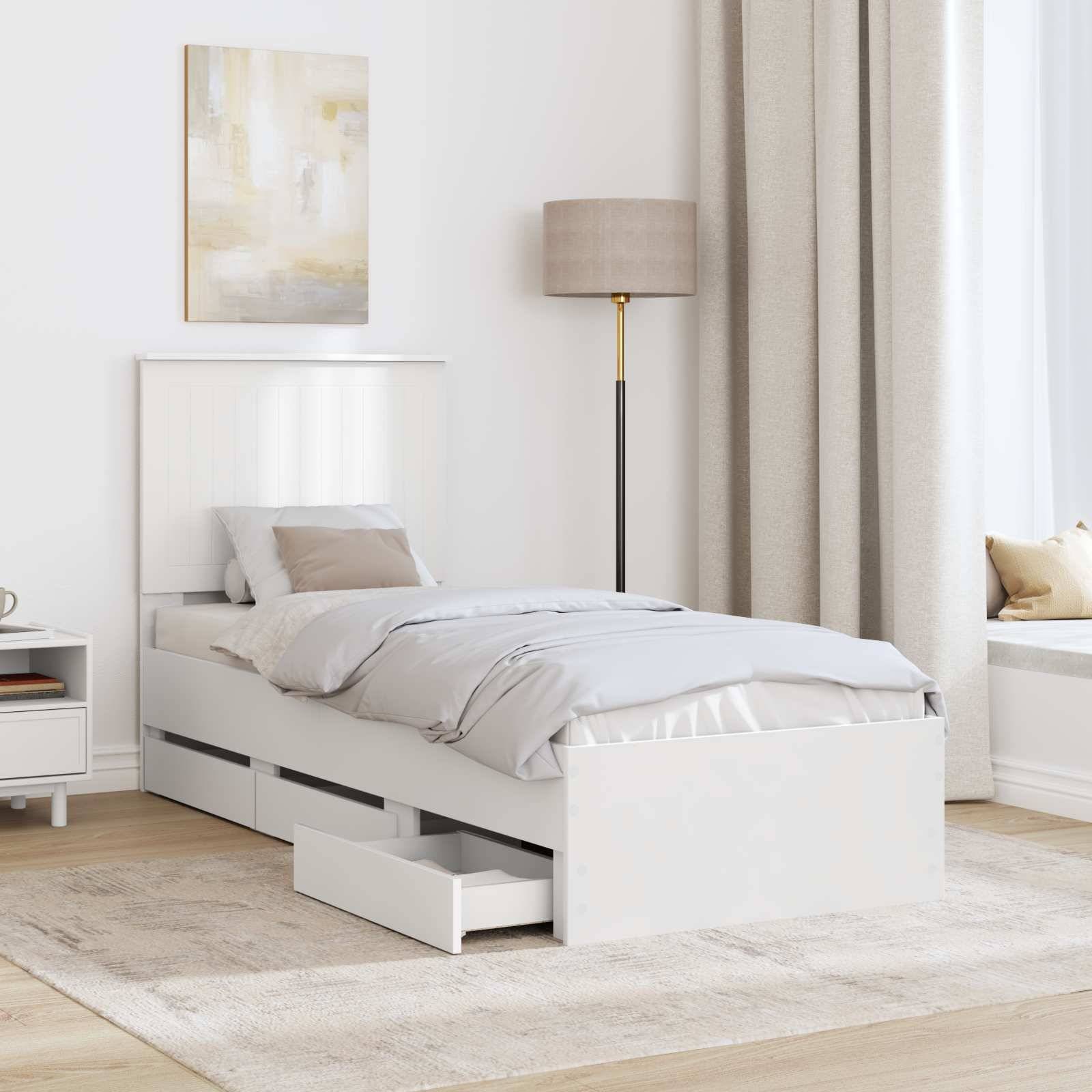 Ein minimalistisches Schlafzimmer mit einem Einzelbett, das Staurageschubladen darunter hat, einem Nachttisch mit Büchern, einer Stehlampe und neutraler Dekoration.