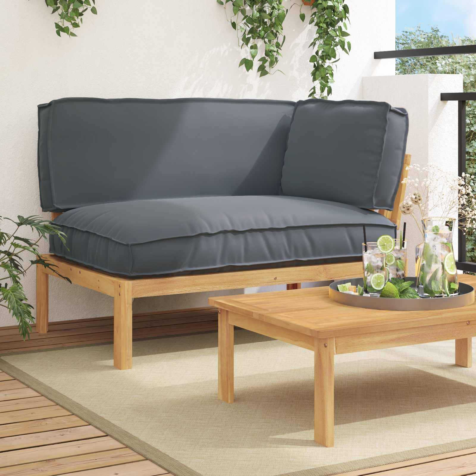 Eine moderne Outdoor-Holzterrasse mit einem grauen gepolsterten Sofa, einem Holzcouchtisch und einem Tablett mit Gläsern und Getränken, umgeben von Pflanzen.