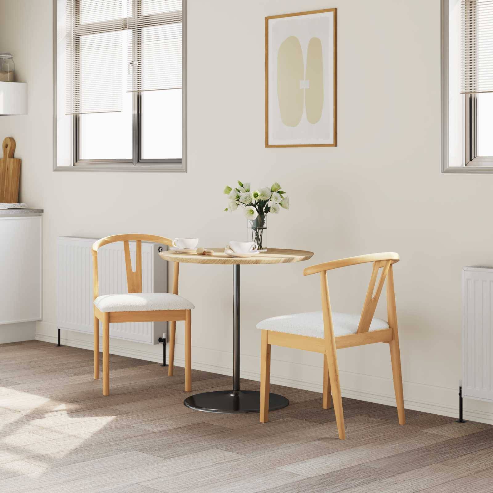 Eine gemütliche Essecke mit einem runden Tisch, zwei Holzstühlen und einer Vase mit Blumen. Sonnenlicht fällt durch die Fenster und eine minimalistisches Kunstwerk hängt an der Wand.