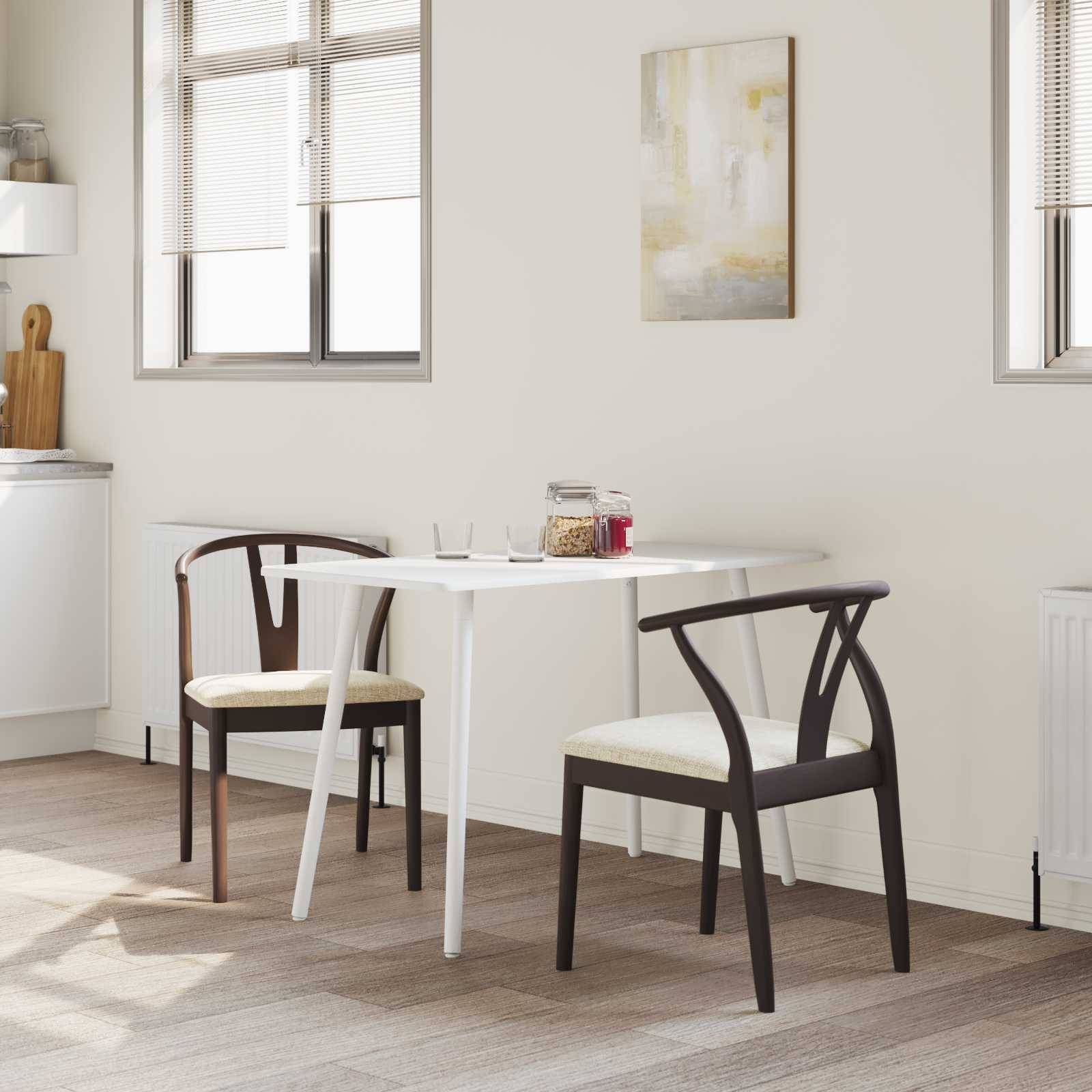 Eine helle Küche mit modernen weißen Küchenschränken, einem runden Tisch mit zwei Stühlen und einem Keksglas auf dem Tisch. Sonnenlicht strömt durch die Fenster.