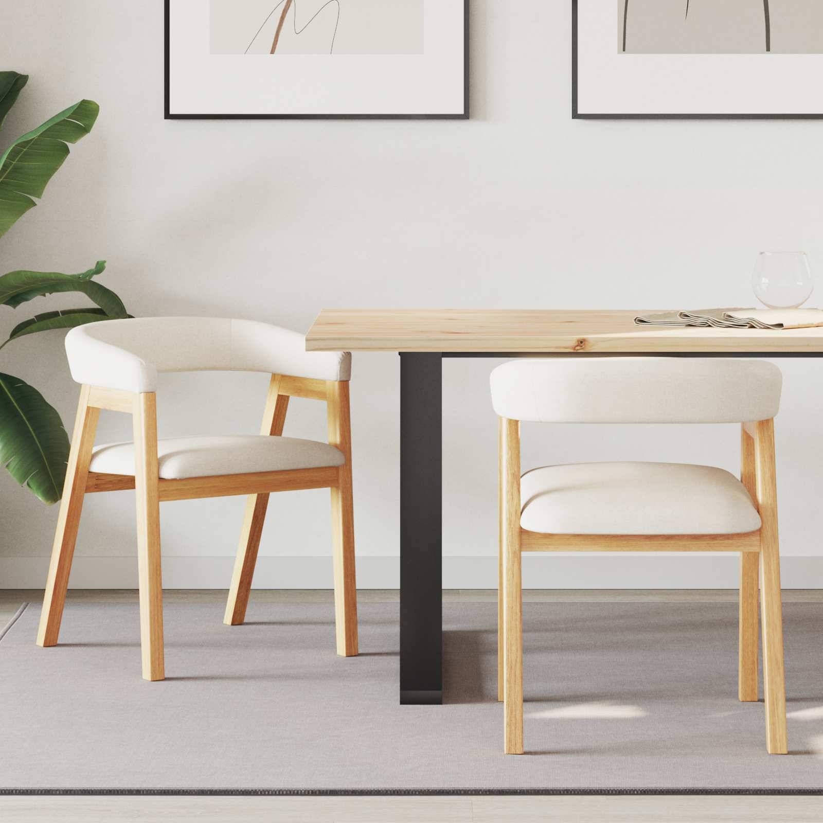 Ein Holzesstisch mit zwei weißen gepolsterten Stühlen in einem modernen Zimmer, mit Pflanzendekoration und gerahmter abstrakter Kunst an der Wand.