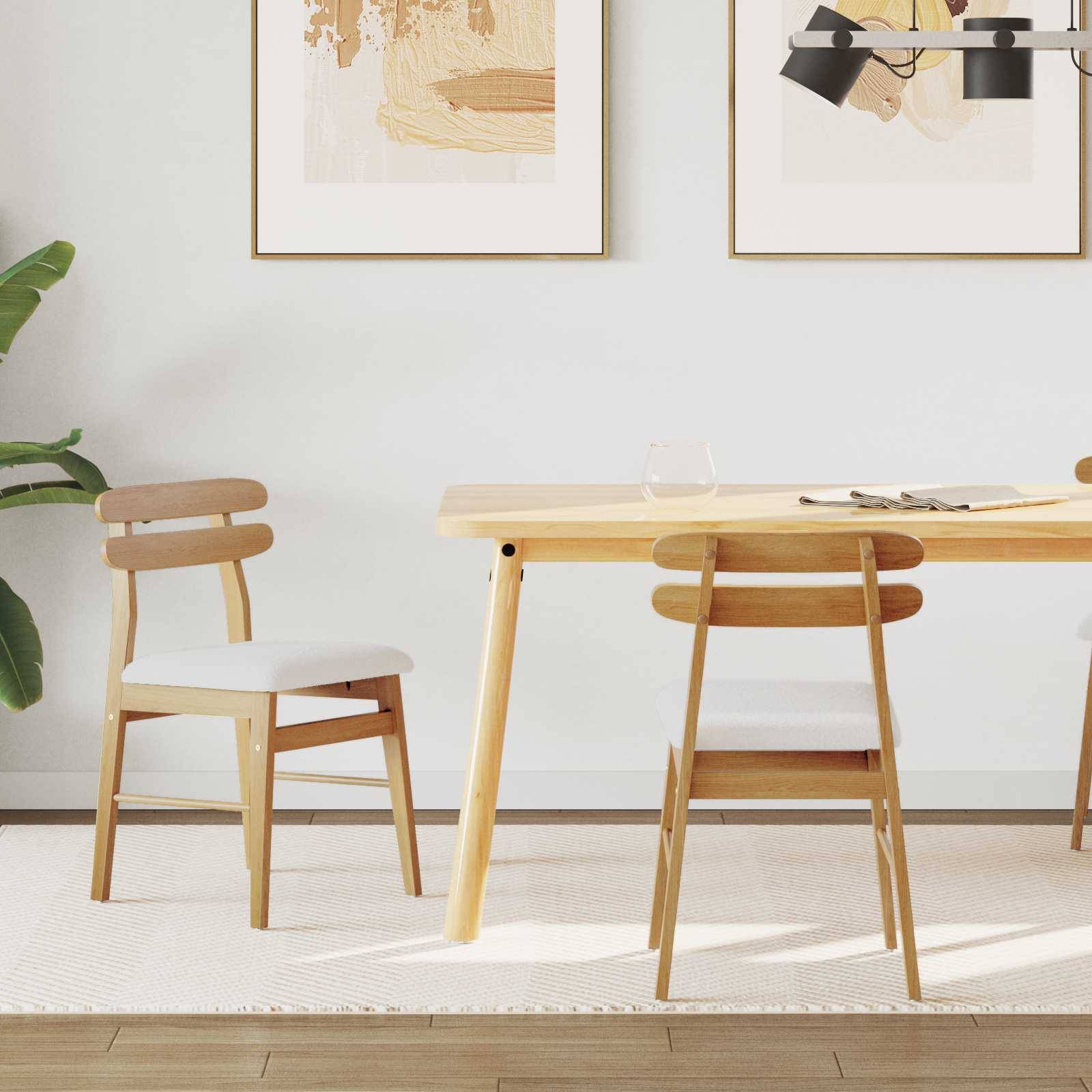 Ein moderner Essbereich mit einem hellen Holztisch, zwei Stühlen und einer Pflanze. Zwei gerahmte abstrakte Kunstwerke hängen an der Wand über dem Tisch.