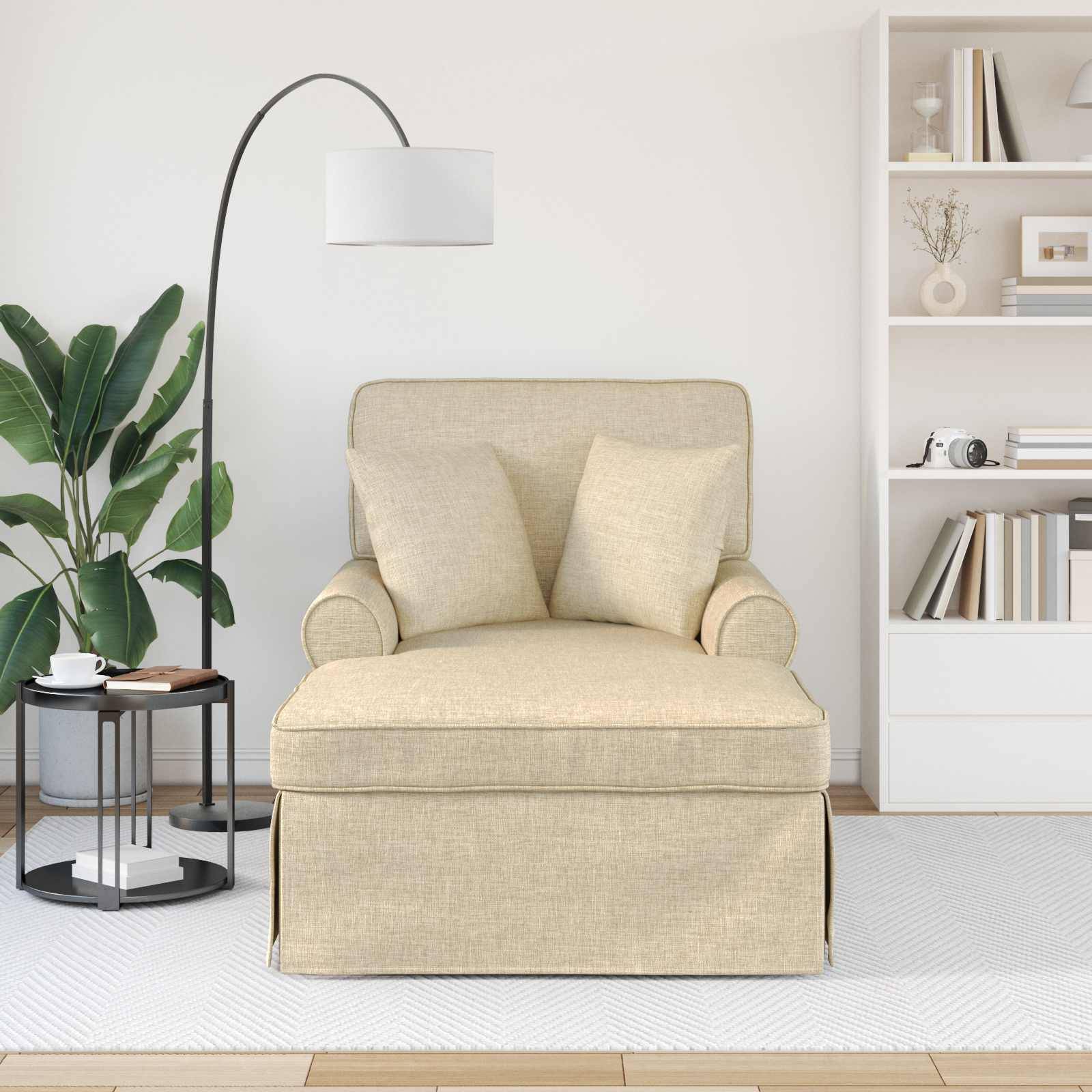 Ein beiger Sessel mit zwei Kissen ist zwischen einer Stehlampe und einem Bücherregal platziert, auf einem hellen Holzboden mit einer Topfpflanze in der Nähe.