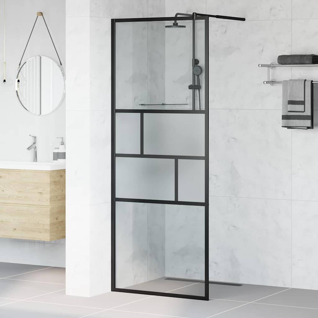 Eine moderne Dusche mit Glasabtrennung und schwarzen Rahmen. Waschbecken mit Spiegel und zusammengelegten Handtüchern auf einem Rack sichtbar.