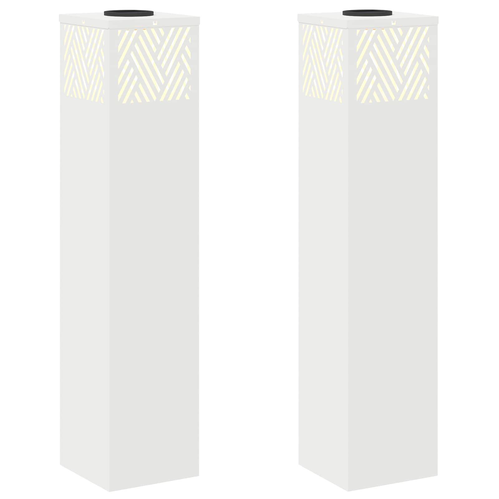 Zwei hohe, weiße rechteckige Säulen mit beleuchteten geometrischen Mustern nahe dem oberen Ende.