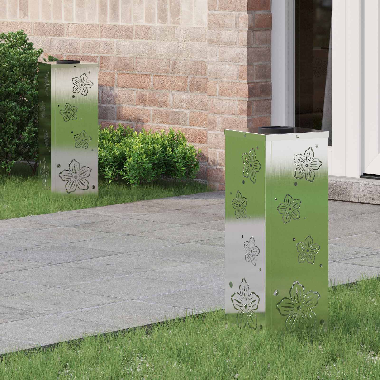 Weg mit zwei grünen Metallpfählen, die mit Blumenmotiven verziert sind, der in einem Garten neben einer Ziegelmauer und einer Glastür liegt.