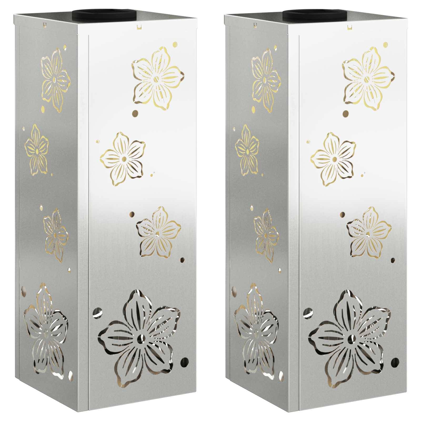 Zwei Laternen aus Edelstahl in rechteckiger Form mit Blumenmotiv-Ausschnitten an den Seiten, die das Licht in Blütenformen hindurchscheinen lassen.