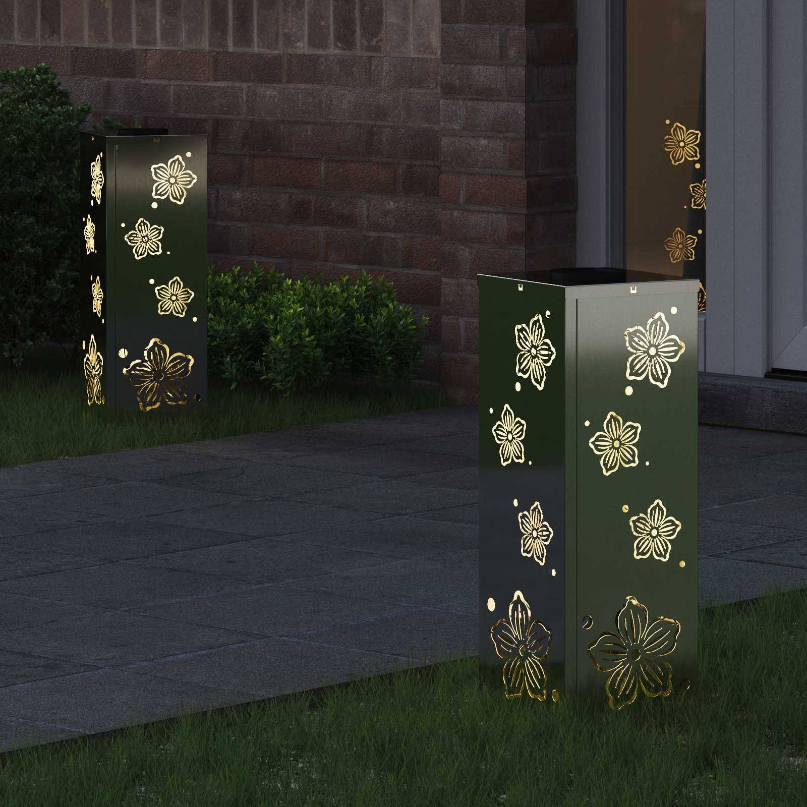 Gartenweg beleuchtet durch rechteckige Laternen, verziert mit Blumenmotiven, die warmes Licht auf das Gras werfen und die Fassade des Backsteingebäudes hervorheben.