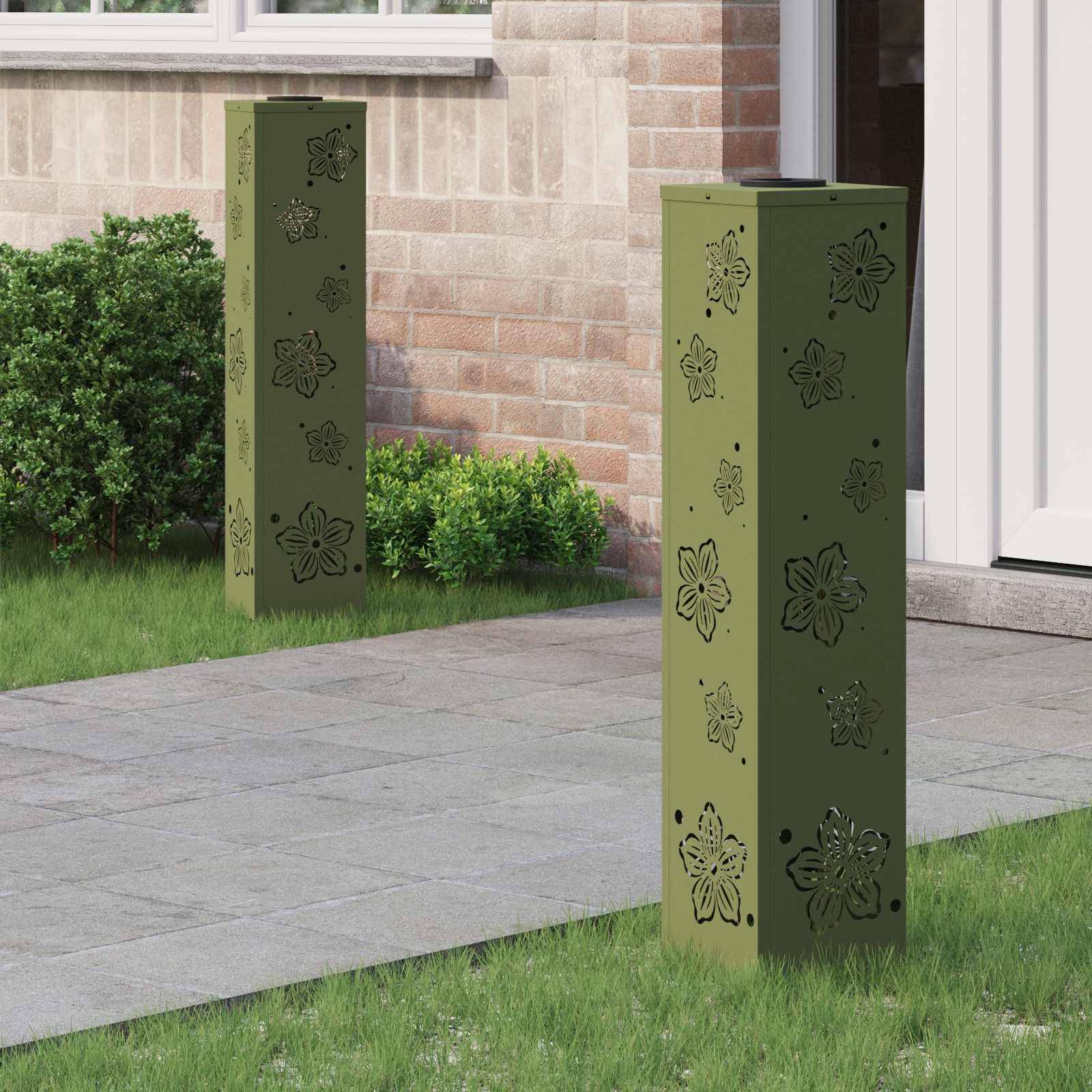 Grüne Metallpfosten mit floralen Ausschnitten stehen auf einem Betonweg neben einem Backsteingebäude und Gebüsch, in der Nähe eines Fensters und einer Tür.