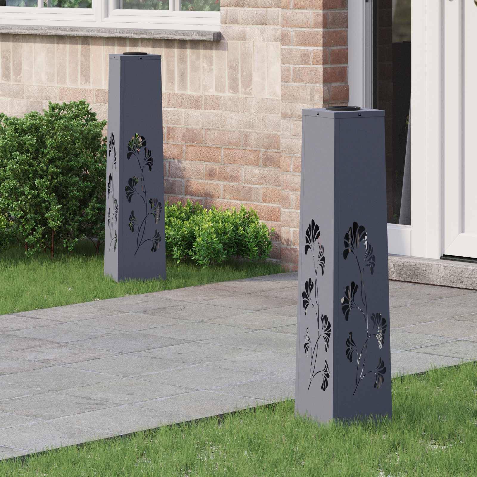 Eine moderne Terrasse mit dekorativen Metalllaternen, die Blattmuster ausgeschnitten haben, steht auf einem gepflasterten Weg in der Nähe einer Ziegelmauer und grüner Sträucher.