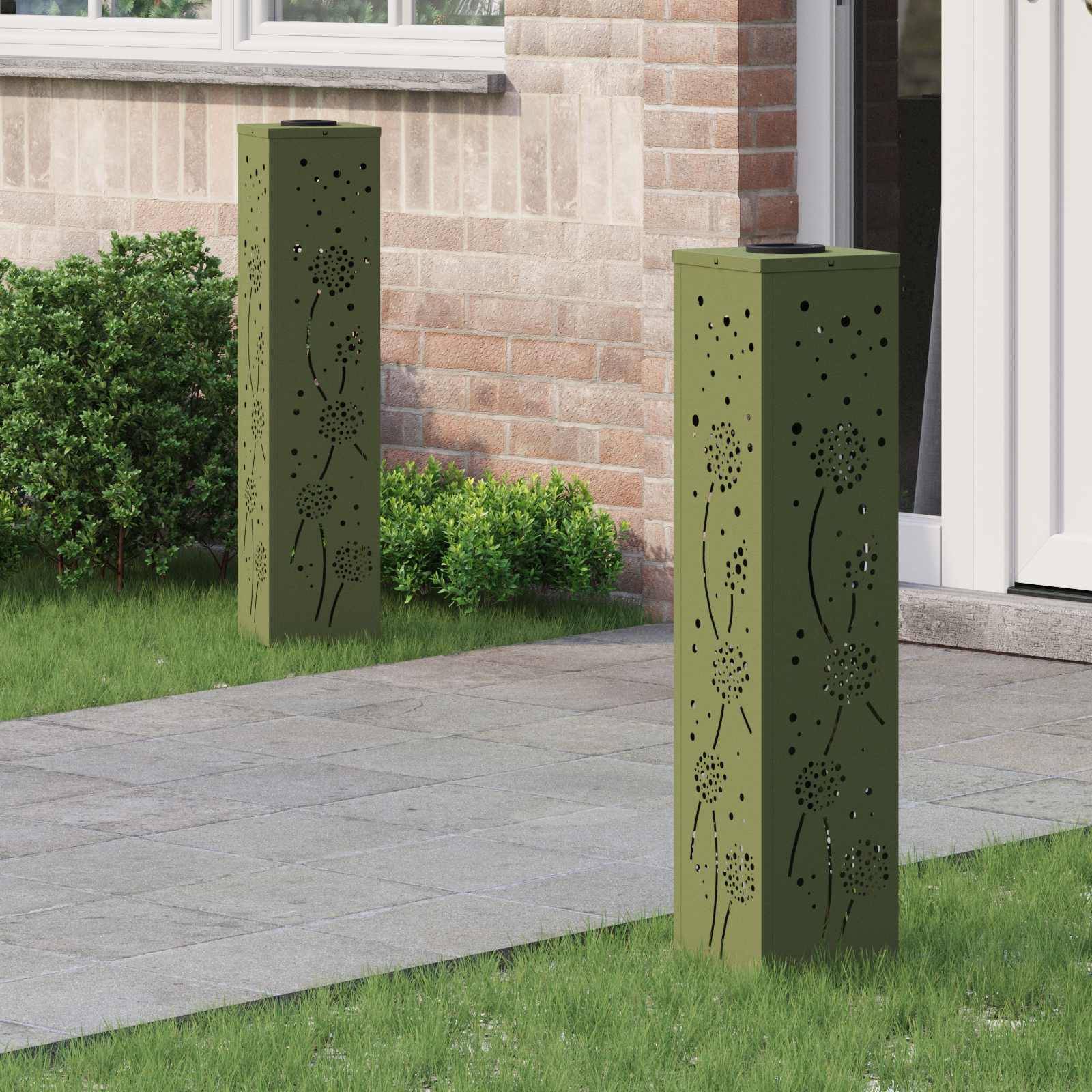 Zwei hohe, grüne Gartenleuchten mit floralen Ausschnittmustern stehen auf einem Steinweg in der Nähe eines Backsteinhauses mit Sträuchern im Hintergrund.