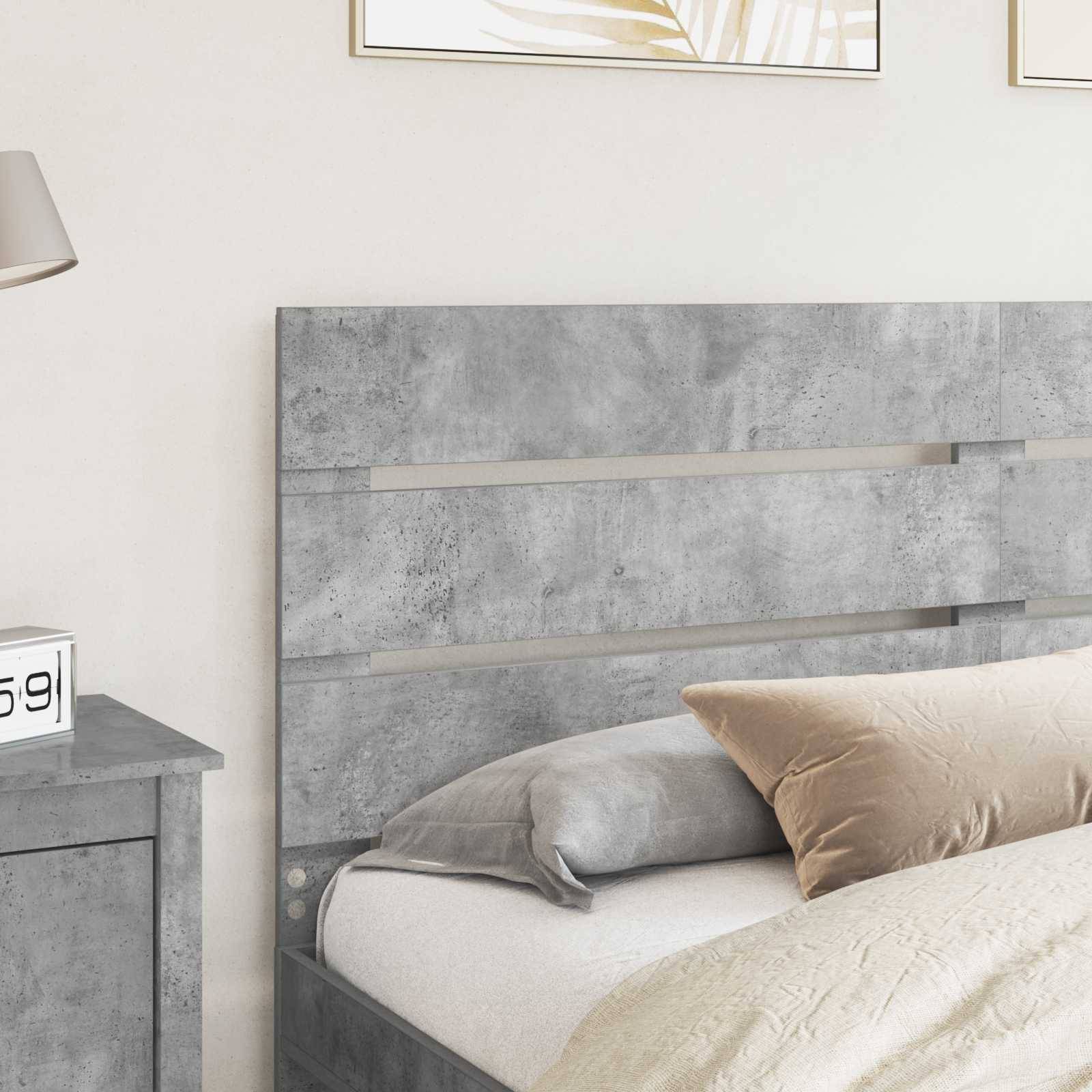 Ein modernes Schlafzimmer mit einem grau strukturierten Betonkopfteil und passendem Nachttisch, mit beigen und grauen Kissen auf einem ordentlich gemachten Bett.