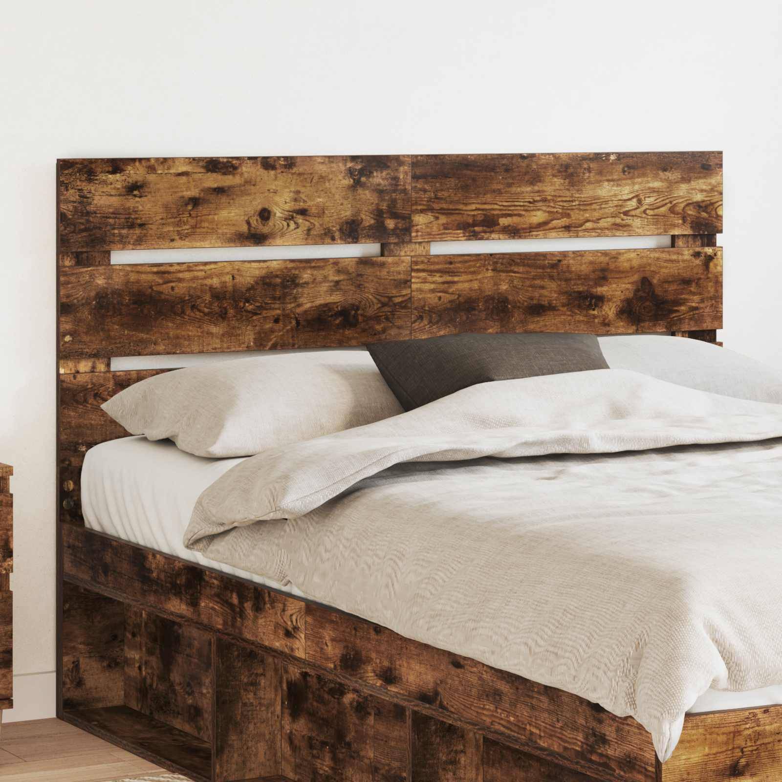 Ein rustikales Holzbett mit hohem Kopfteil, weißer Bettwäsche und einem einzelnen dunklen Kissen in einer minimalistischen Schlafzimmereinrichtung.