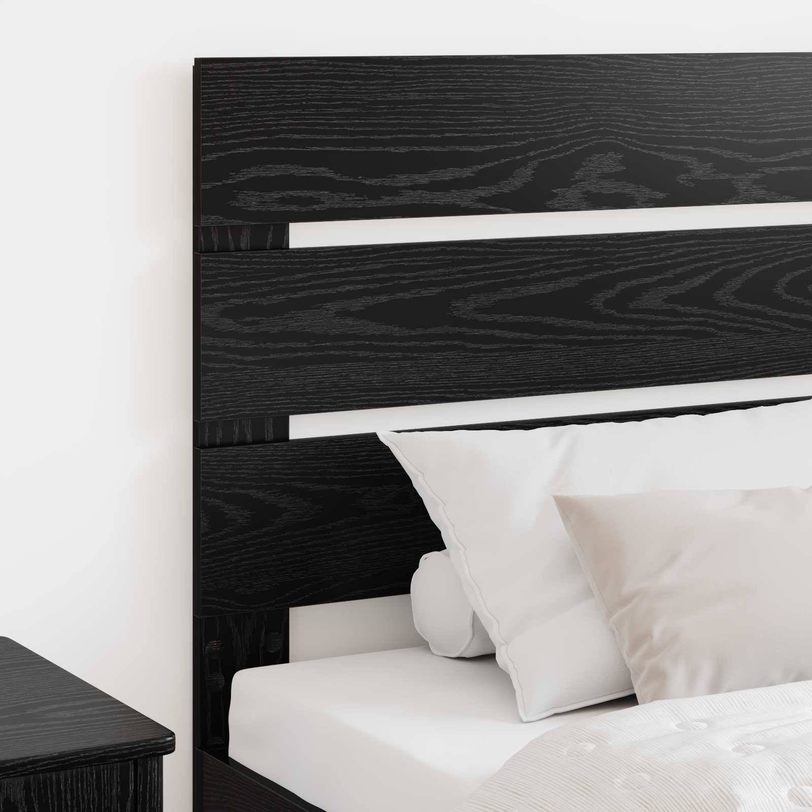 Ein sorgfältig gemachtes Bett mit weißen Kissen vor einem dunkelholzernen Kopfteil in einer minimalistischen Schlafzimmereinrichtung.
