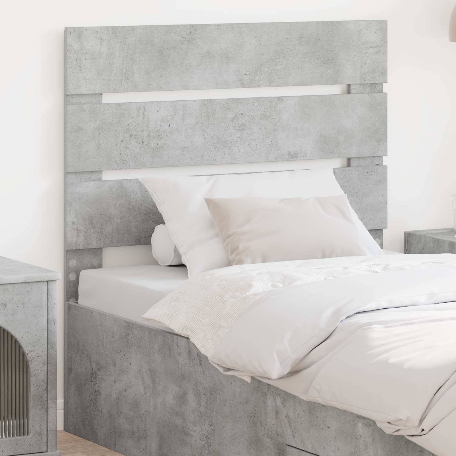 Ein modernes Schlafzimmer mit einem minimalistischen grauen Bett mit betongemustertem Kopfteil, weißer Bettwäsche und einem kleinen Nachttisch.