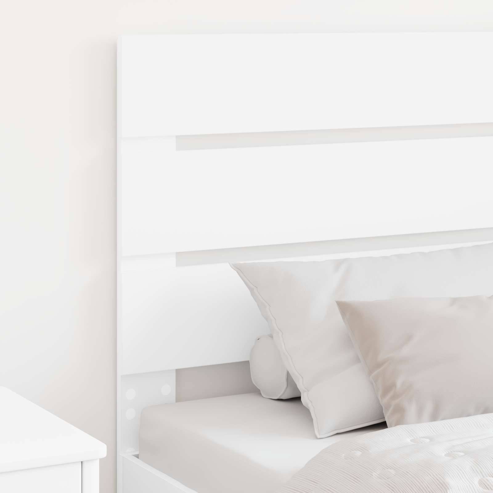 Ein modernes weißes Bett mit einem Holzkopfteil, verziert mit weichen, neutral gefärbten Kissen und einer hellgrauen Decke in einem minimalistischen Schlafzimmer.