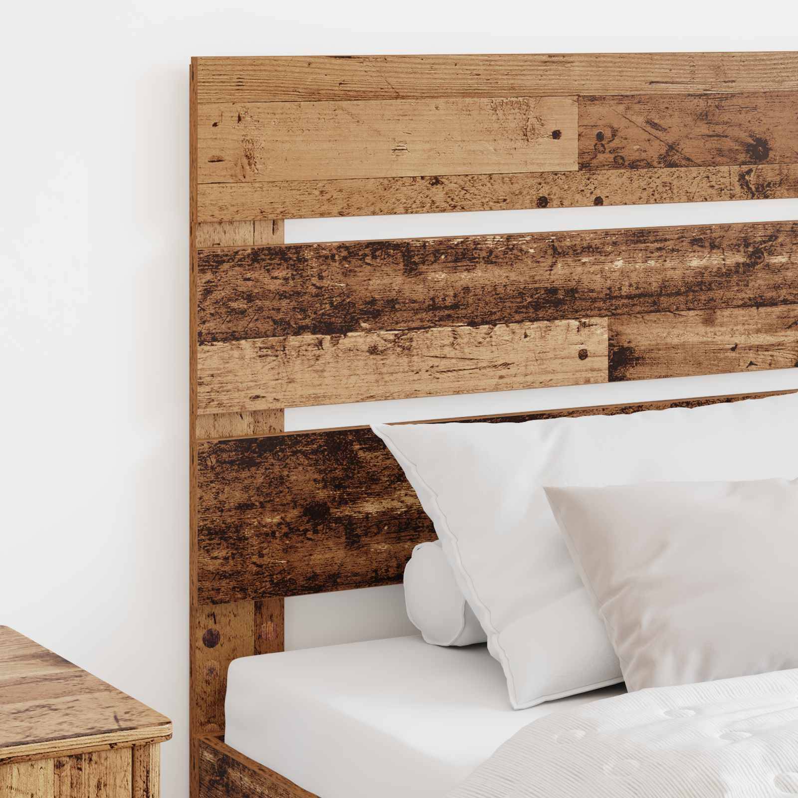 Ein rustikales Holzkopfteil mit verwittertem Finish ist an einem Bett mit weißen Kissen und Laken befestigt. Ein Holznachttisch steht daneben.
