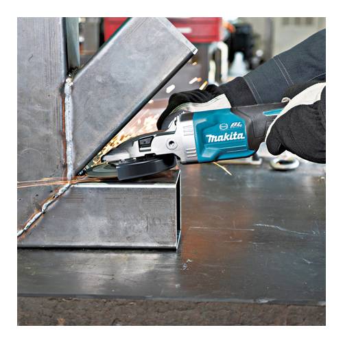 Eine Person, die einen Makita-Winkelschleifer benutzt, um die Schweißnähte an einer Metallstruktur zu glätten, wobei Funken umherfliegen. Der Arbeiter trägt Schutzhandschuhe.