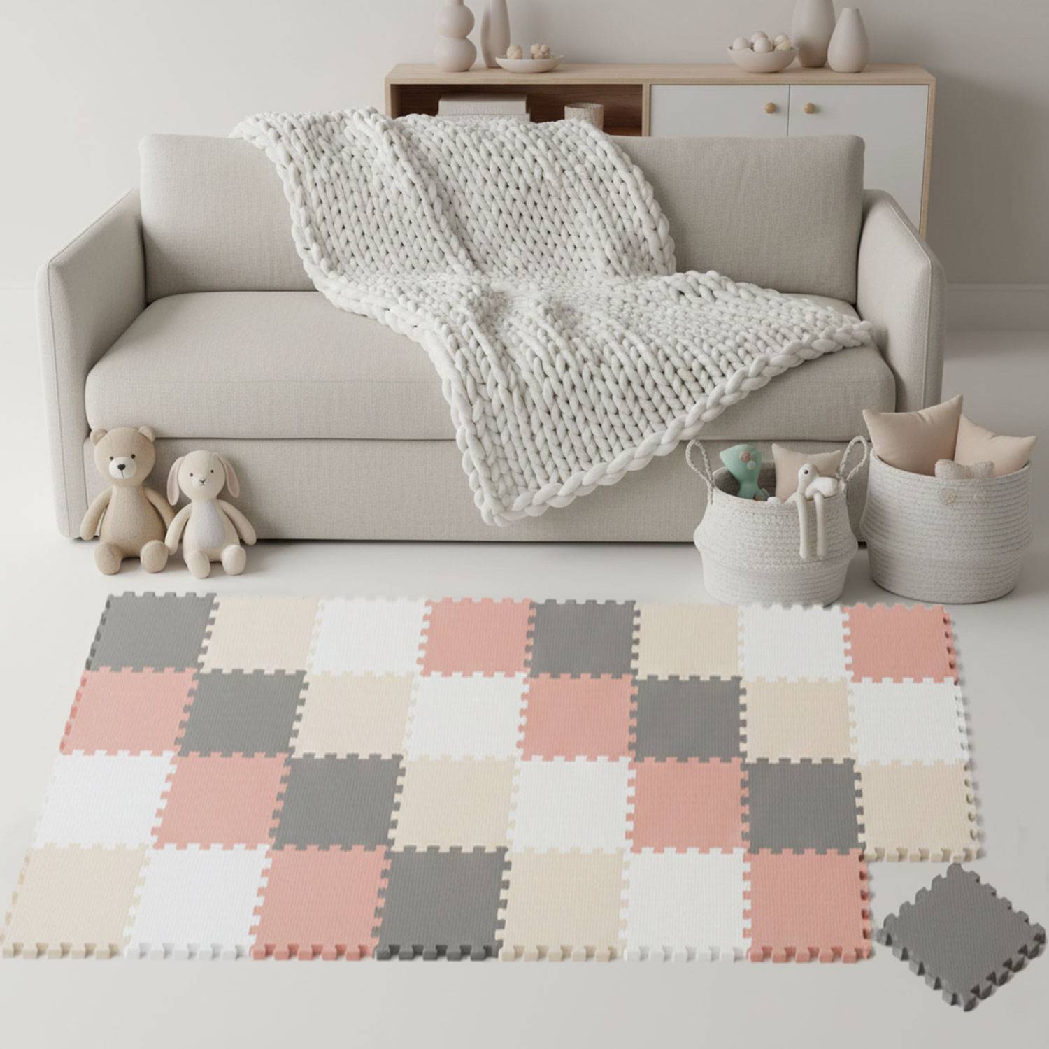 Ein gemütliches Wohnzimmer mit einem beigen Sofa, über das eine gestrickte Decke gebreitet ist. Weiche Spielzeuge sitzen auf einer Seite, neben einer farbenfrohen karierten Spielmatte.