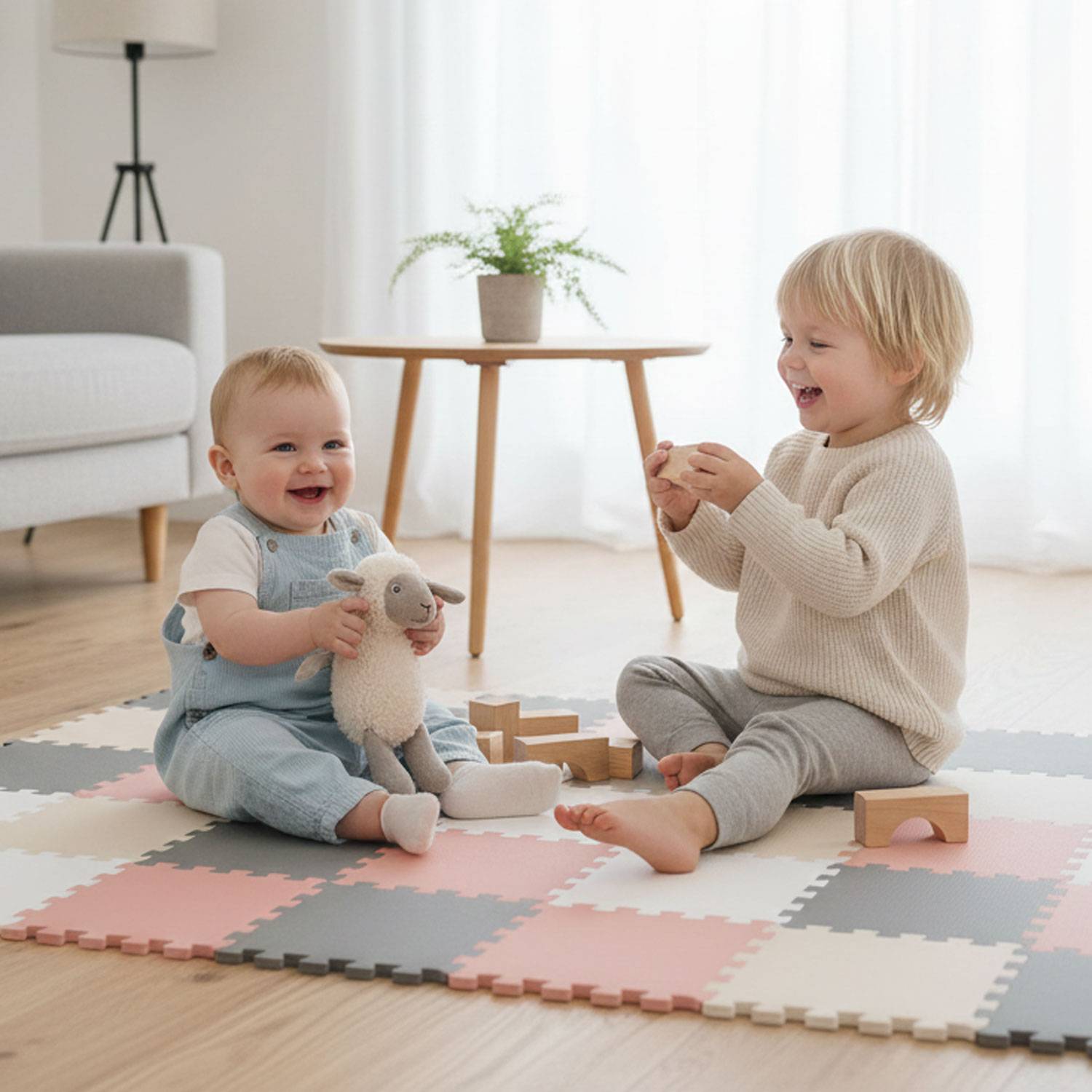 Zwei Kleinkinder spielen auf einer bunten Schaumstoffmatte mit Spielzeug in einem Wohnzimmer. Eines hält ein Stofftier-Lamm, und das andere baut mit Holzklötzen.