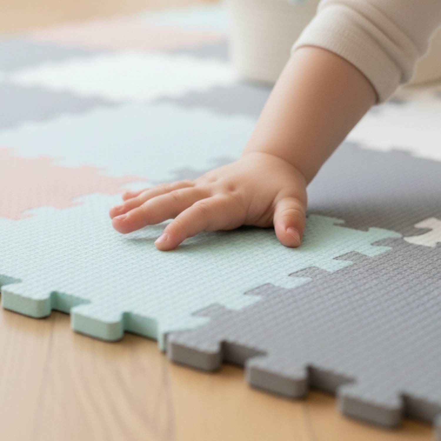 Eine Kinderhand ruht auf verschachtelten Schaumstoffbodenfliesen in Pastellfarben und konzentriert sich auf Texturen und spielerische Interaktion.