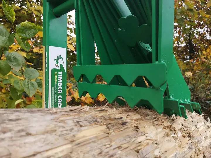 Ein grünes Holzspaltwerkzeug im Einsatz, das einen Baumstamm effizient spaltet. Der Hintergrund zeigt Herbstlaub. Die Marke 'Timber Croc' ist sichtbar.