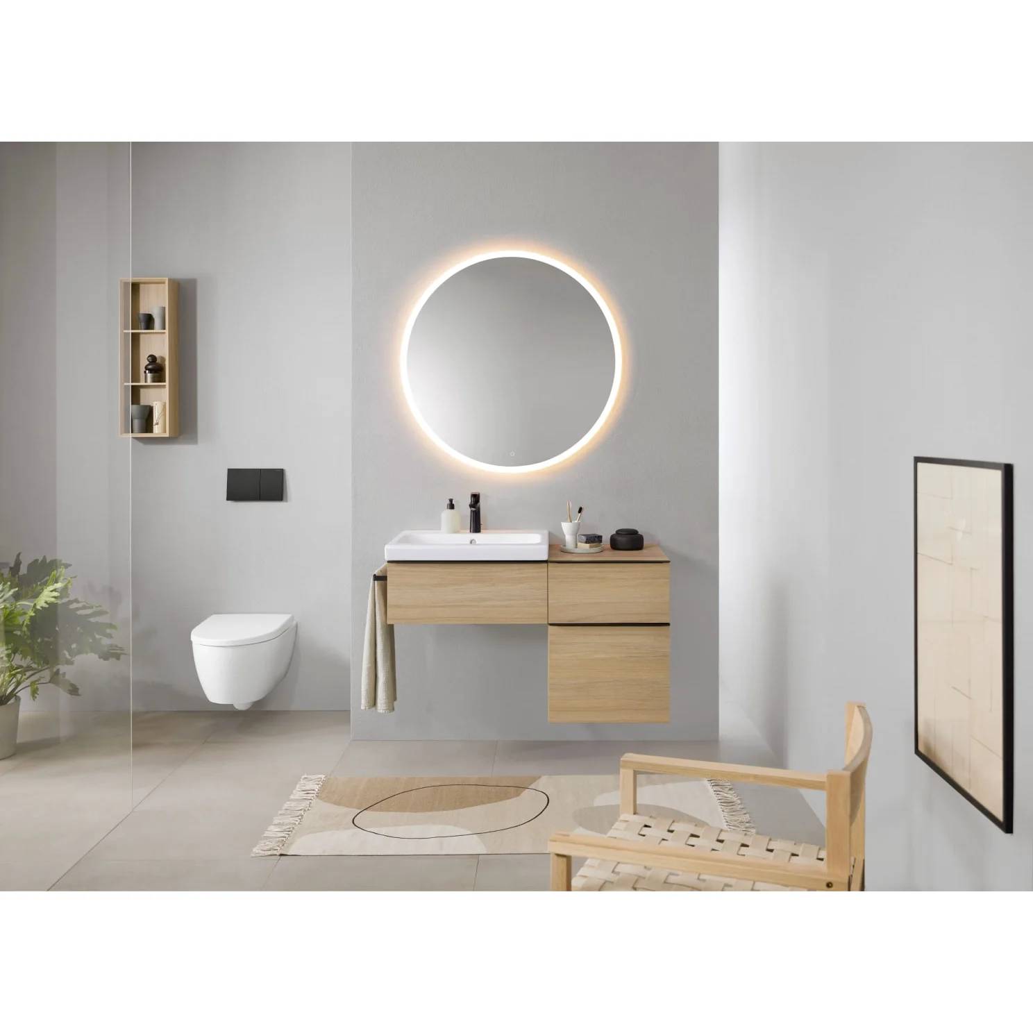 Modernes Badezimmer mit an der Wand montiertem Toilette, schwebendem Holzwaschtisch, rundem beleuchteten Spiegel und Holzstuhl auf einem Teppich