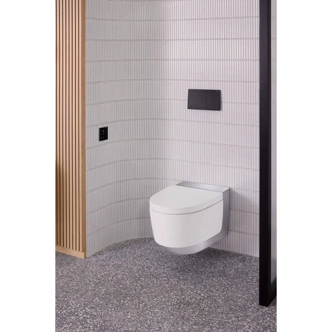 Modernes Badezimmerecke mit an der Wand montierter weißer Toilette, schwarzer Spülplatte, weiß gekachelten Wänden, Holzlattenverkleidung und gefliestem Boden mit Sprenkeleffekt.