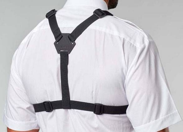 Eine Person trägt eine schwarze Haltungskorrektur über einem weißen Hemd und zeigt verstellbare Riemen und ein unterstützendes Rückendesign.