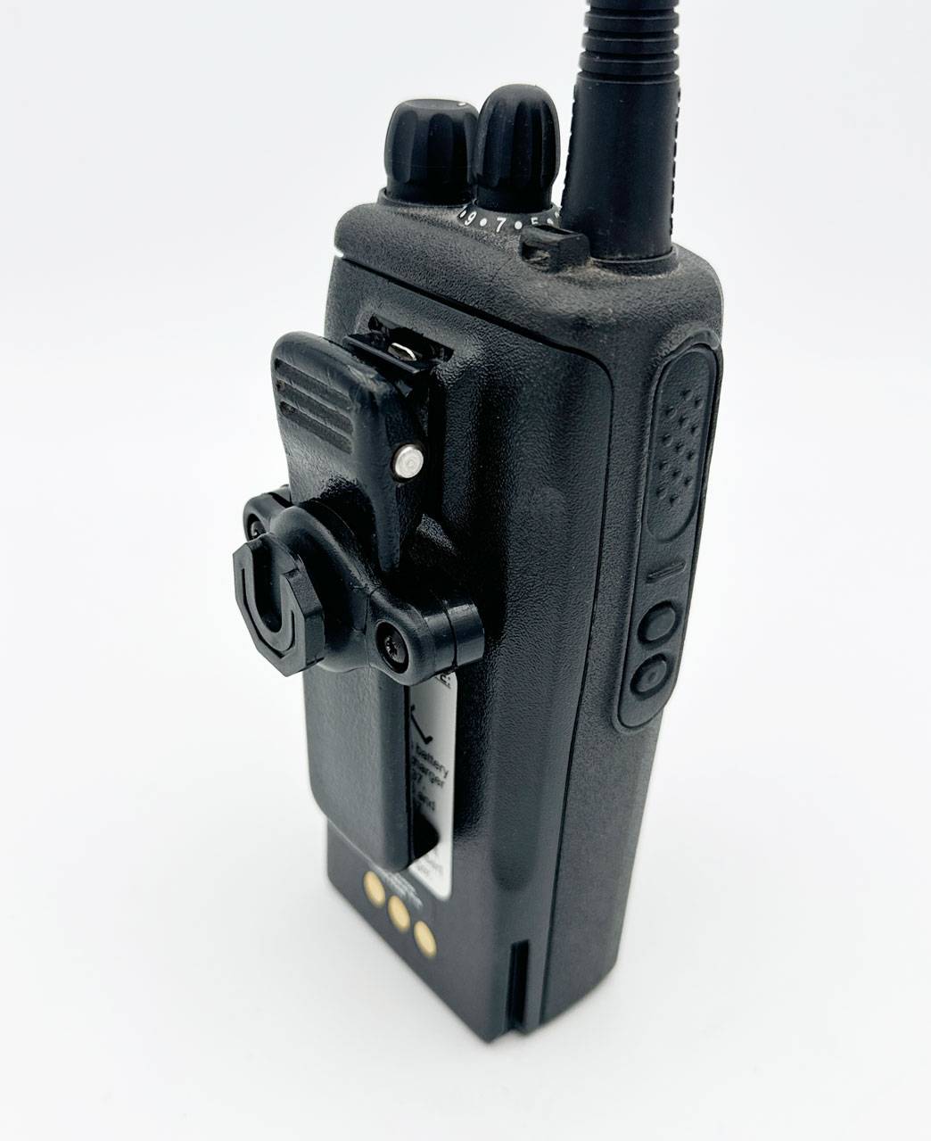 Ein dunkles tragbares Funkgerät mit angebrachtem Gürtelclip verfügt über eine oben montierte Antenne, Lautstärke- und Kanalregler sowie Seitentasten zur Bedienung.