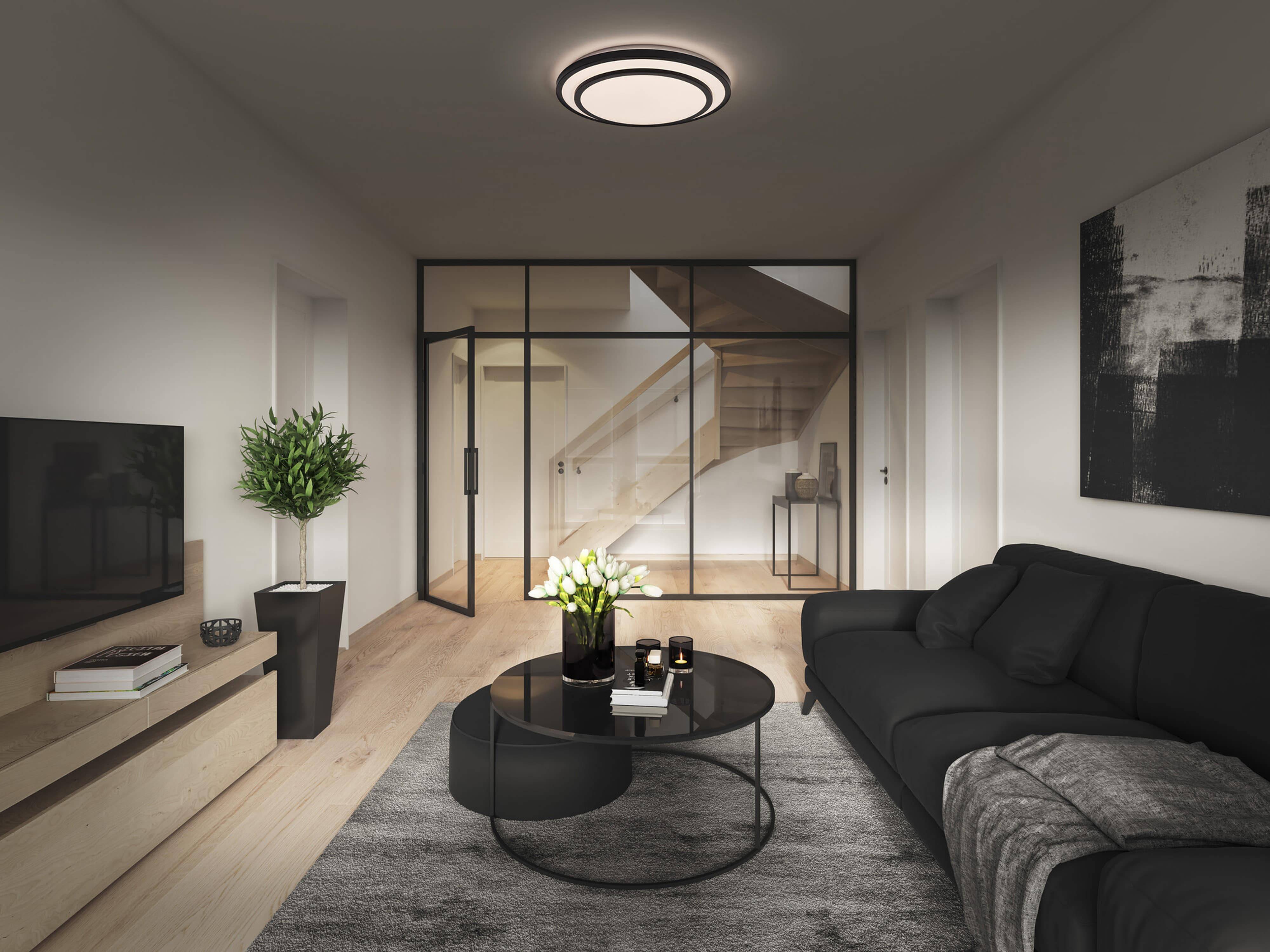 Ein gemütliches Wohnzimmer mit einem modernen Sofa mit blauen und grauen Kissen, einem hölzernen Couchtisch und einer hohen grünen Pflanze in der Ecke.