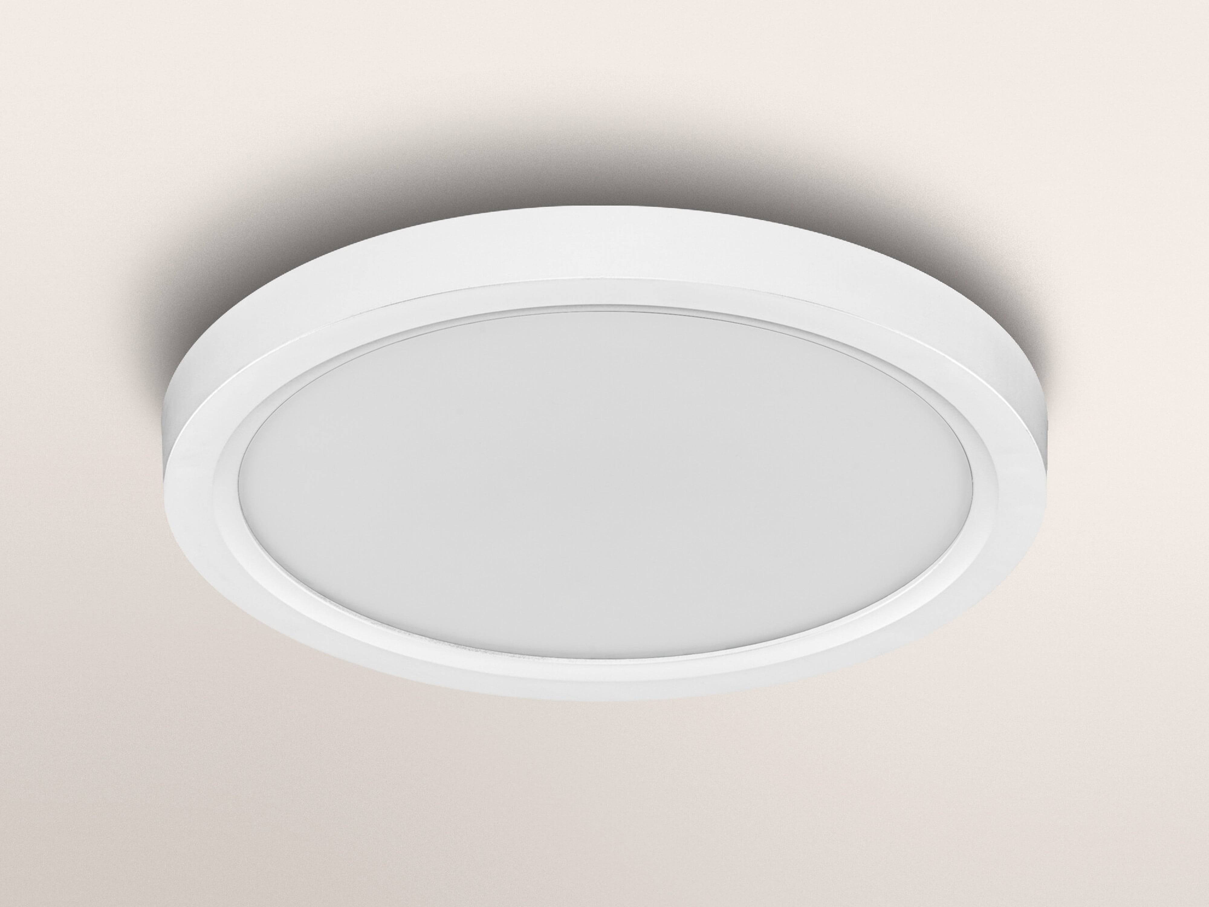 Eine schlanke, runde weiße Deckenleuchte mit minimalem Design, auf einer hellen Decke montiert, die Beleuchtung spendet.