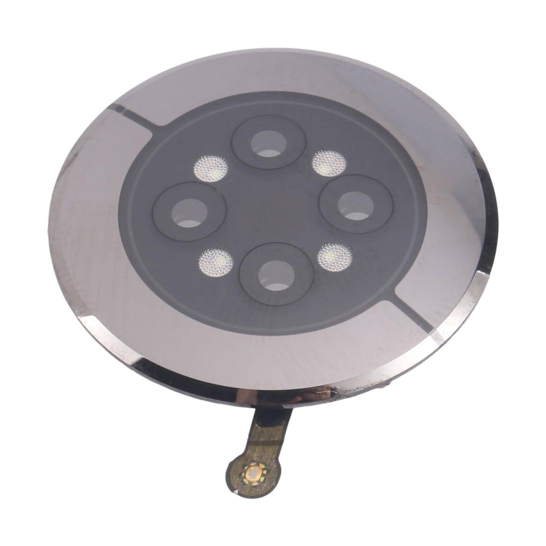 Ein rundes, metallisches Objekt mit fünf kreisförmigen Öffnungen und einer kleinen vorstehenden Lasche am Rand, möglicherweise ein Ersatzteil oder Filterkomponente.