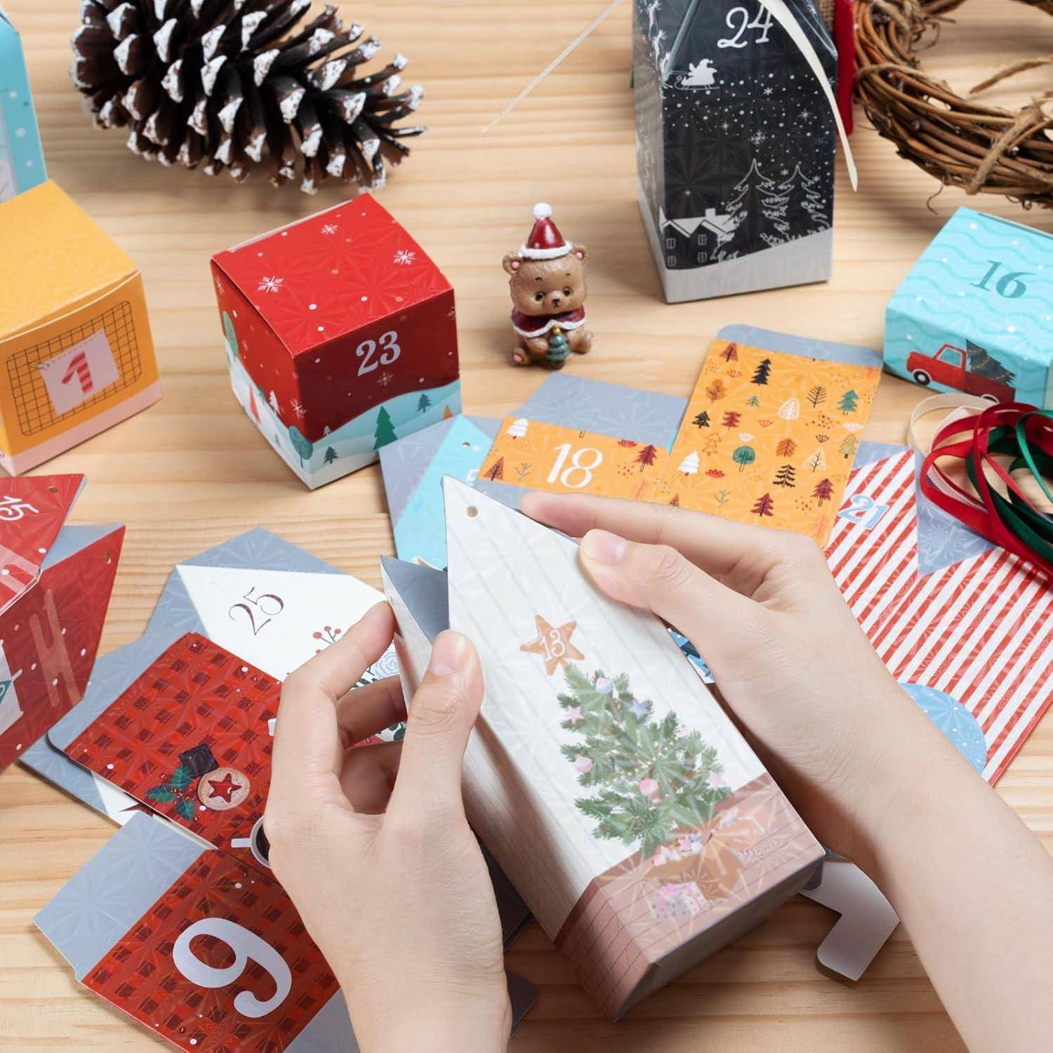 Hände, die mit einem weihnachtlich gestalteten Adventskalender aus bunten, nummerierten Kästchen auf einem Holztisch interagieren, mit Dekorationen in der Nähe.