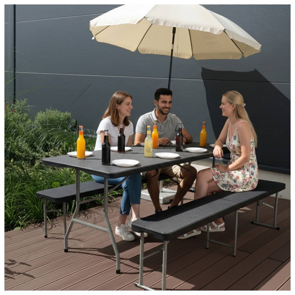 Drei Personen sitzen an einem Tisch im Freien unter einem Sonnenschirm, genießen Getränke und unterhalten sich. Flaschen und Teller liegen auf dem Tisch.