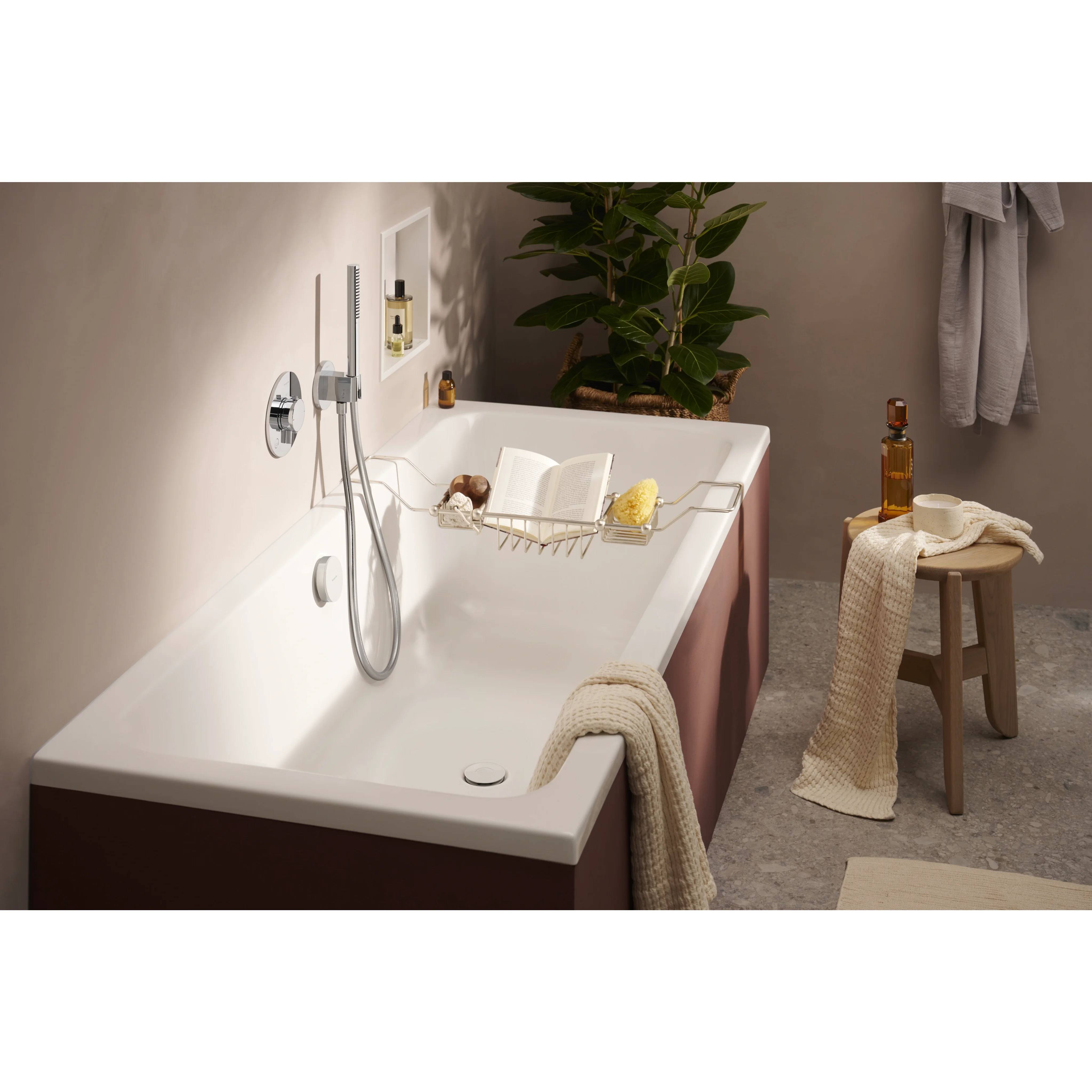 Modernes Badezimmer mit einer weißen freistehenden Badewanne, Duscharmatur, Hocker, Handtüchern und Badezimmeraccessoires, die eine spa-ähnliche Atmosphäre schaffen.