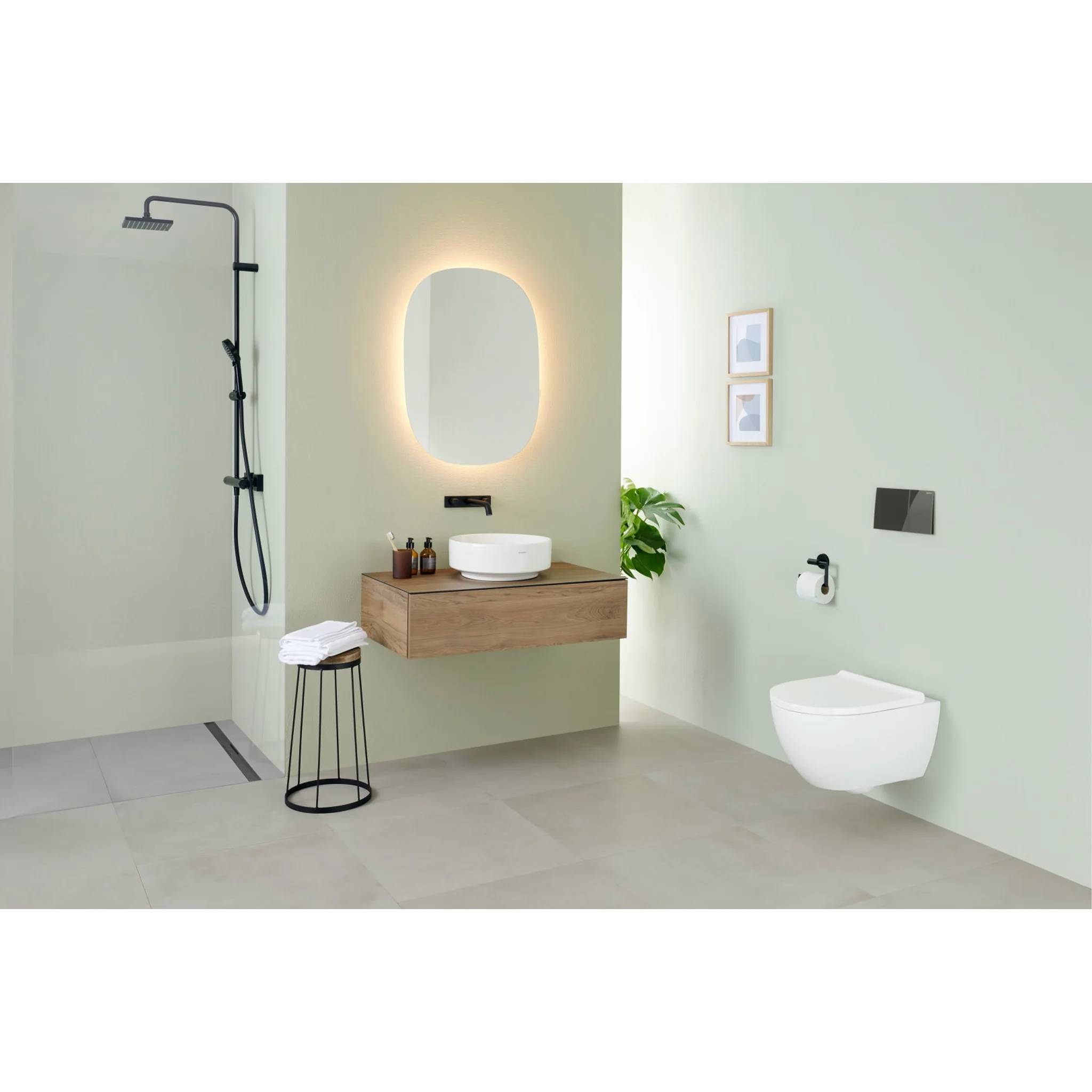 Modernes minimalistes Badezimmer mit begehbarer Dusche, schwebendem Holzwaschbecken und beleuchtetem ovalem Spiegel, wandmontierter Toilette und blassgrünen Wänden.