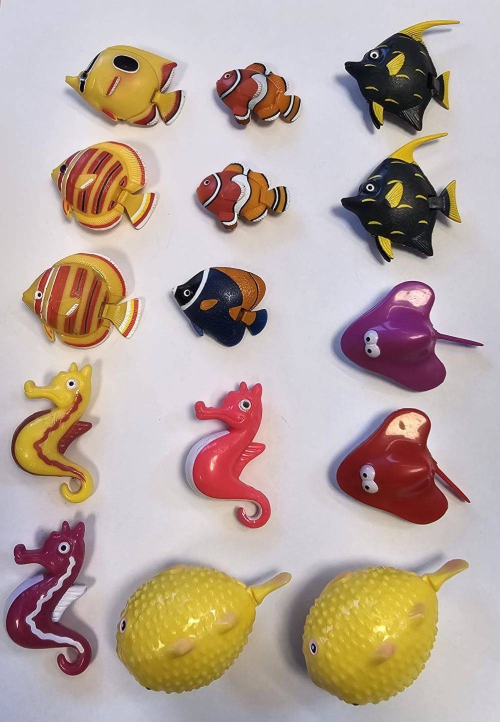 Bunte Spielzeug-Meereswesen, einschließlich Fische, Seepferdchen und Rochen, auf einer weißen Oberfläche angeordnet.