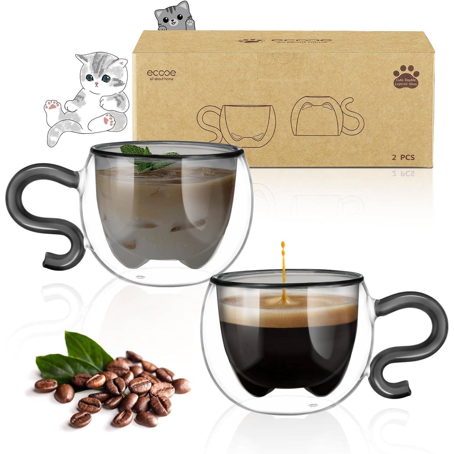 Zwei durchsichtige Kaffeetassen mit Henkeldesigns, die Katzenschwänzen ähneln. Eine enthält Eiskaffee mit Minze, die andere Espresso. Kaffeebohnen in der Nähe. Karton mit Illustrationen im Hintergrund.