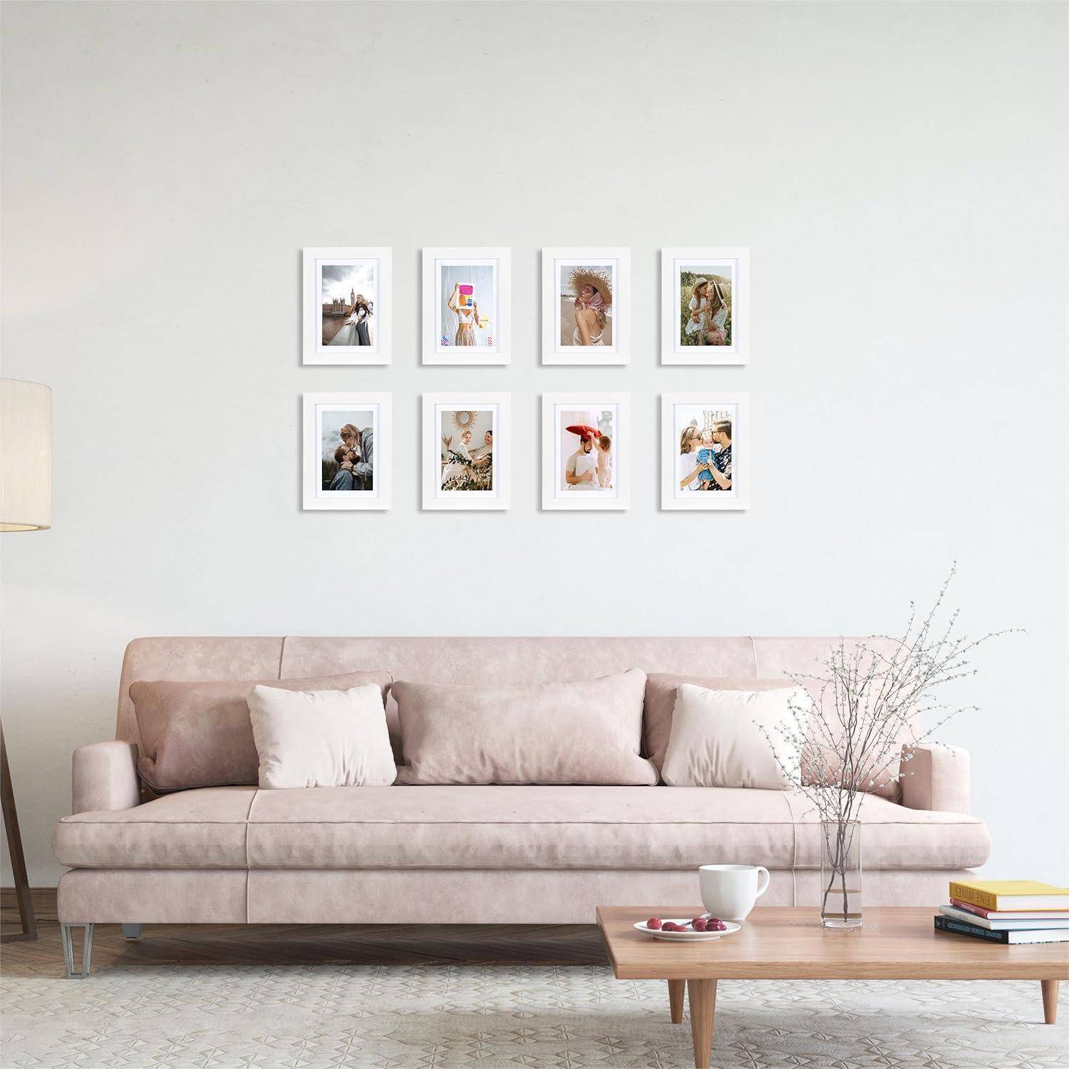 Ein modernes Wohnzimmer mit einem hellrosa Sofa, einer Stehlampe und gerahmten Fotos an der Wand. Ein kleiner Tisch mit einer Vase steht davor.