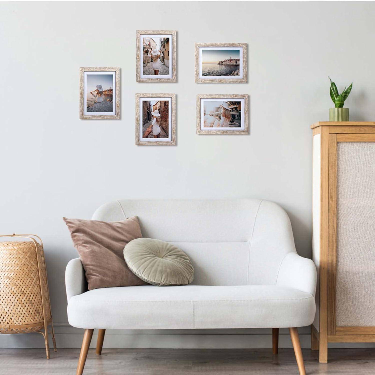 Ein gemütliches Wohnzimmer mit einem weißen Sofa, runden Kissen und dekorativer Rattanmöbel. Fünf gerahmte Reisefotos sind an der Wand angeordnet.