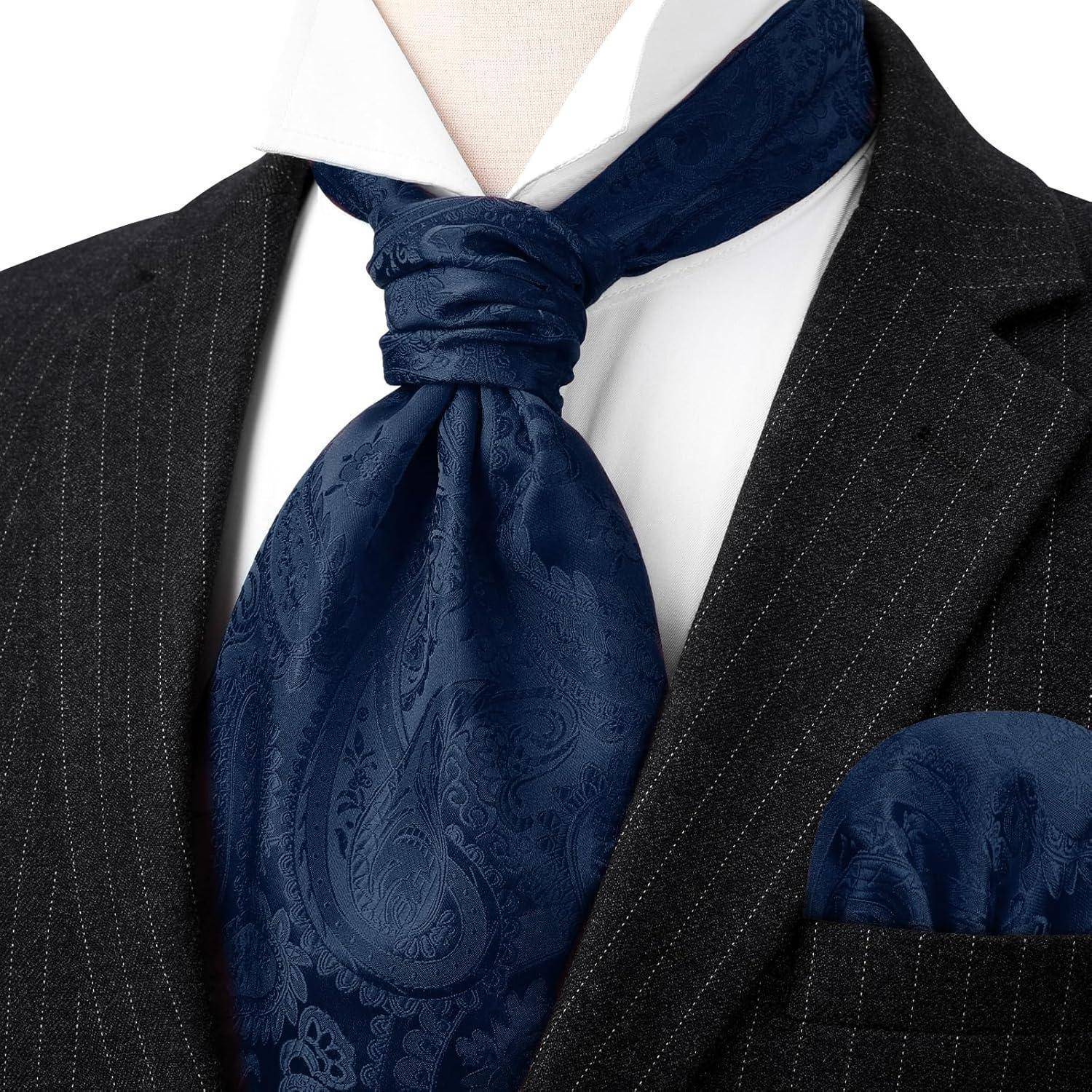 Eine Nahaufnahme eines formellen Outfits mit einem dunklen Nadelstreifenanzug, weißem Hemd sowie blauer paisleymusterter Krawatte und Einstecktuch.