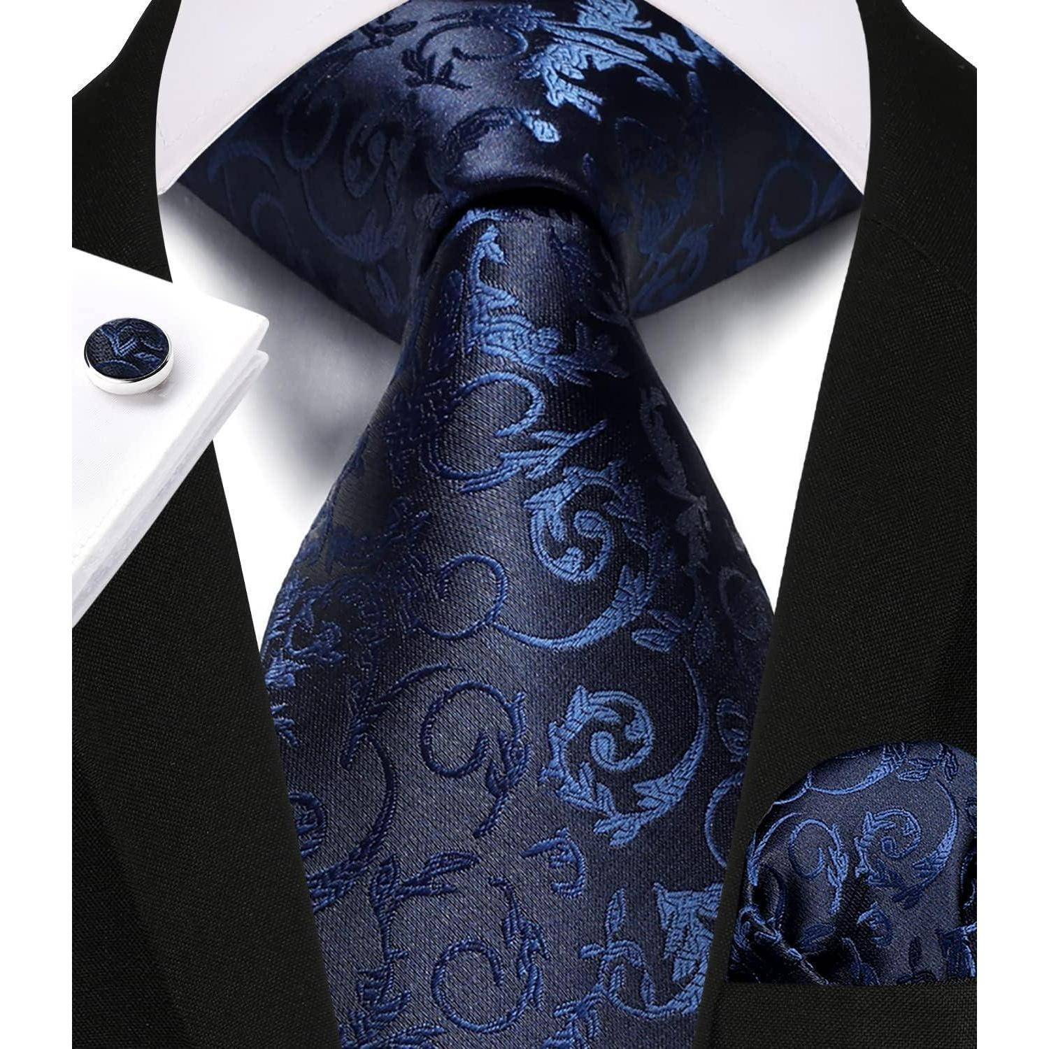 Eine Nahaufnahme eines formellen Anzugs mit einer schwarzen Jacke, einem weißen Hemd und einer blauen gemusterten Krawatte sowie einem Einstecktuch.