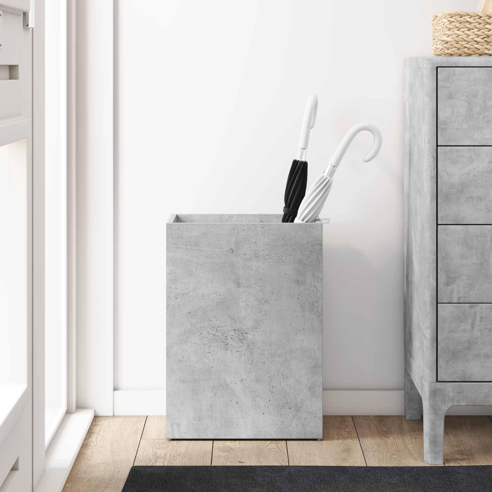 Ein grauer Betonschirmständer hält zwei Schirme neben einer modernen Kommode auf einem Holzboden und schafft einen stilvollen und minimalistischen Eingangsbereich.