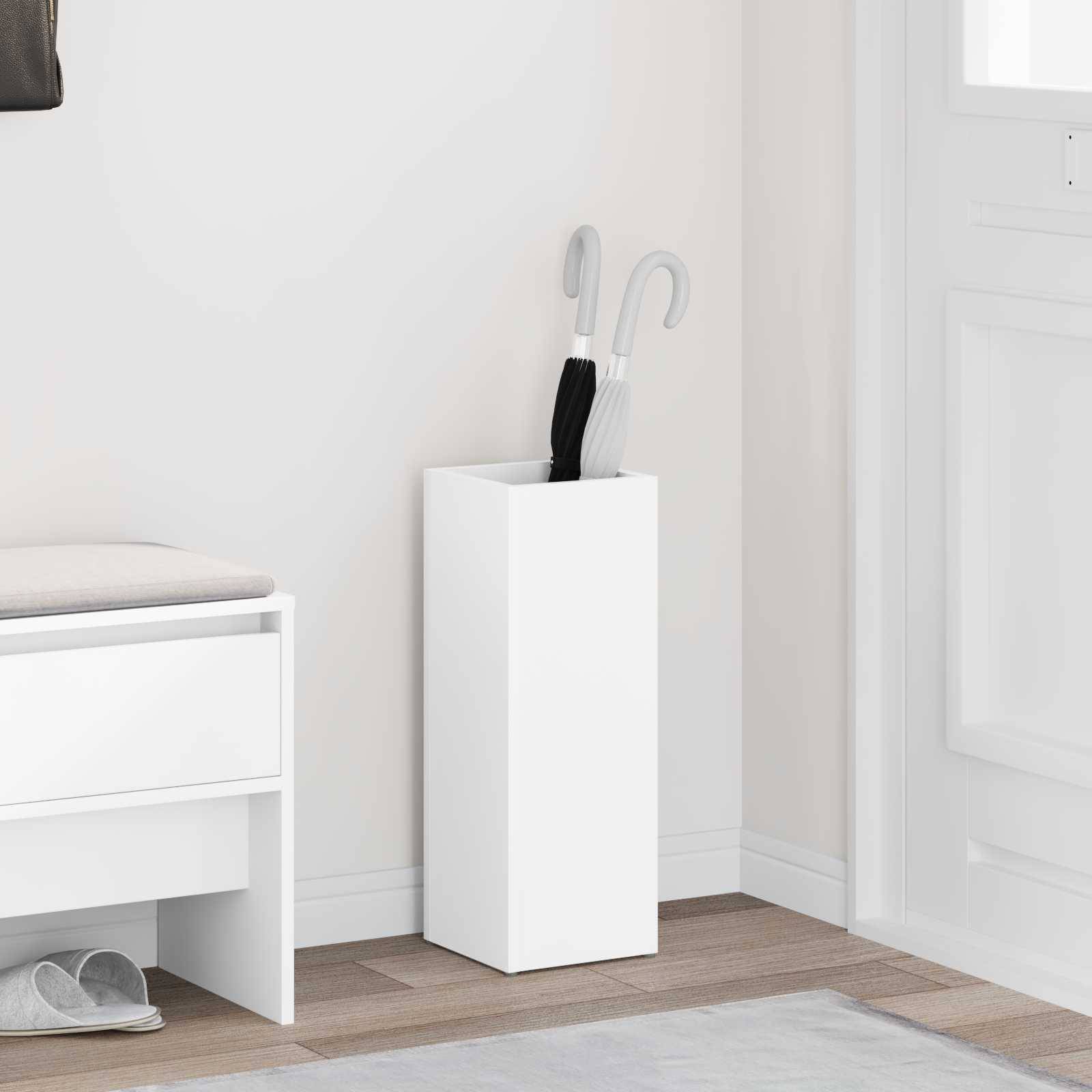 Ein weißer Flur mit einer Schuhbank und einem weißen Schirmständer, der schwarze und weiße Schirme neben einer Tür hält.