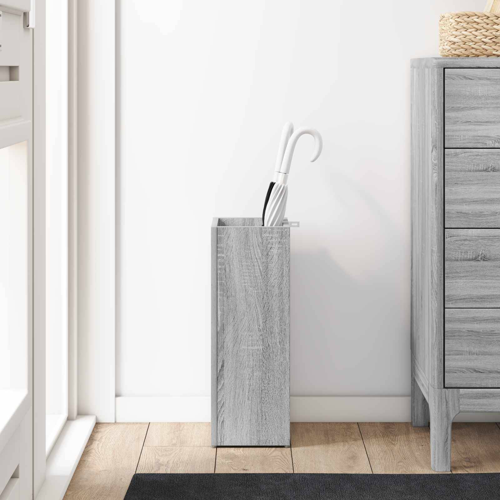Eine minimalistische Ecke mit einem hellgrauen Holz-Aufbewahrungsständer, der eine weiße Toilettenbürste neben einer passenden Kommode enthält.