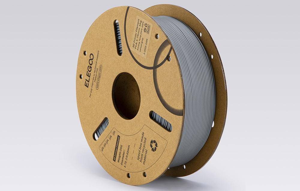 Eine Spule grauen 3D-Druckerfilaments mit der Beschriftung 'ELEGOO', entwickelt für den 3D-Druck, mit sichtbaren Produktinformationen und Recycling-Symbol.