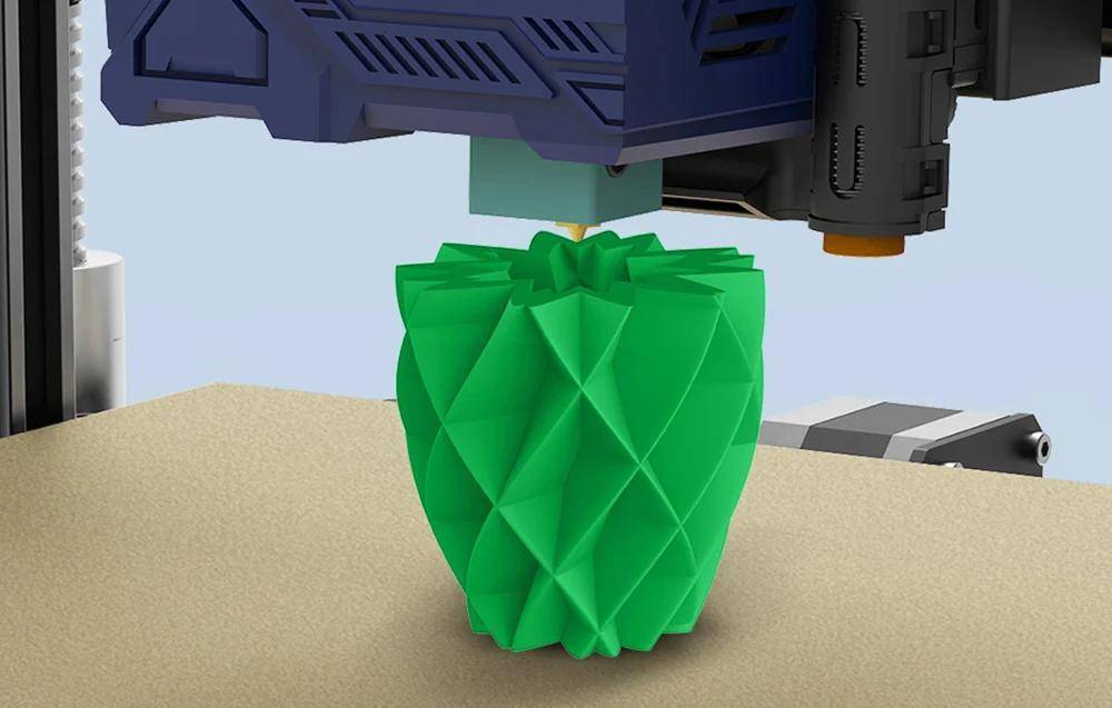 Ein 3D-Drucker, der eine grüne, geometrische Vase mit komplexen Facetten erstellt. Die Düse trägt Material Schicht für Schicht ab.