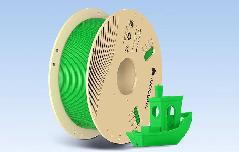 Eine Spule grünes 3D-Druckerfilament neben einem kleinen, grünen, bootförmigen 3D-Druckmodell, beide auf einem hellblauen Hintergrund.