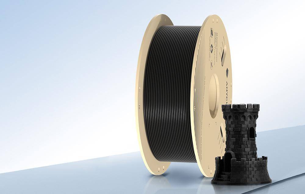 Eine große Rolle schwarzen 3D-Druckerfilaments steht aufrecht, mit einem kleinen, detaillierten Modell eines Burgturms, der daneben auf einer ebenen Oberfläche platziert ist.